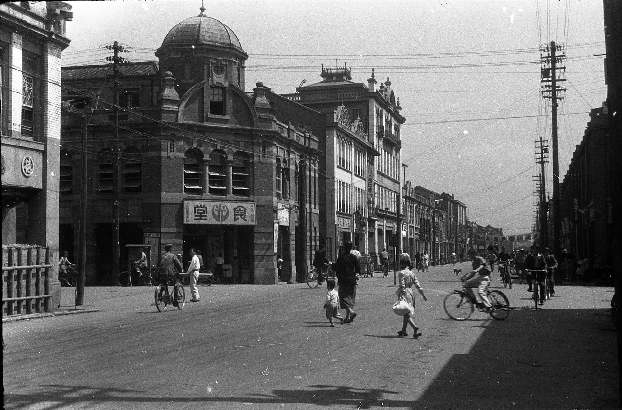 Taiheichō St. 太平町通, Dadaocheng with a “modern” streetscape with a domed building (Hikaru Restaurant 光食堂) and a four-storied building (Chotoryu Shoko Store 張東隆商行). Photograph by Li Huo-Zheng 李火增, a Taiwanese photographer during the colonial era. Wikicommons