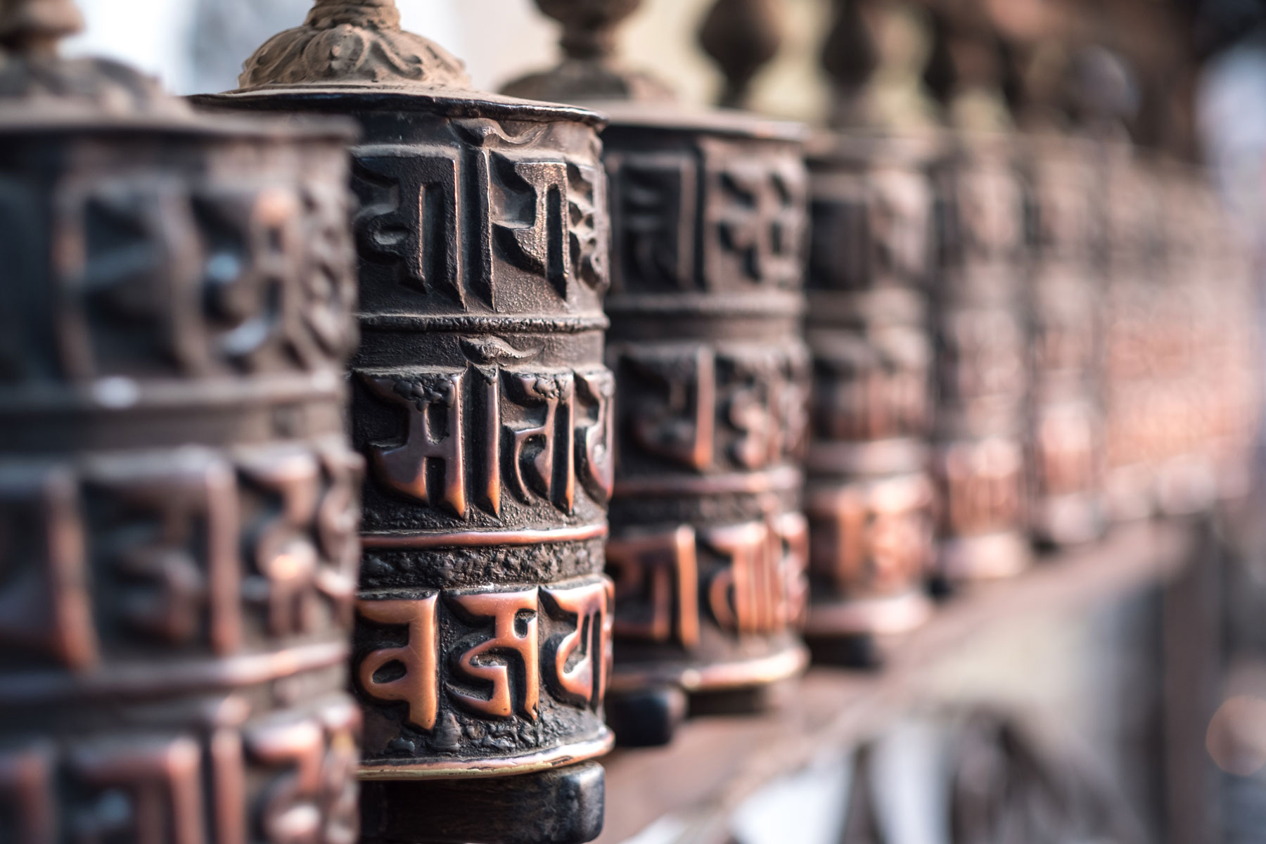 Close-up photograph of ancient prayer wheels in a Buddhist temple in Kathmandu, Nepal. (Source: AdobeStock 246891185)